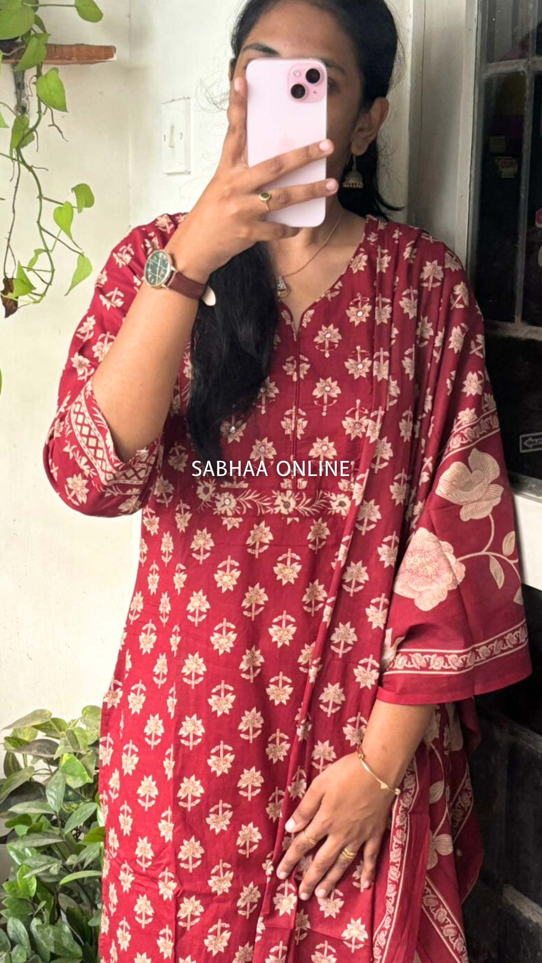 Person wearing a red floral dress with 'SABHAA ONLINE' branding, taking a mirror selfie.